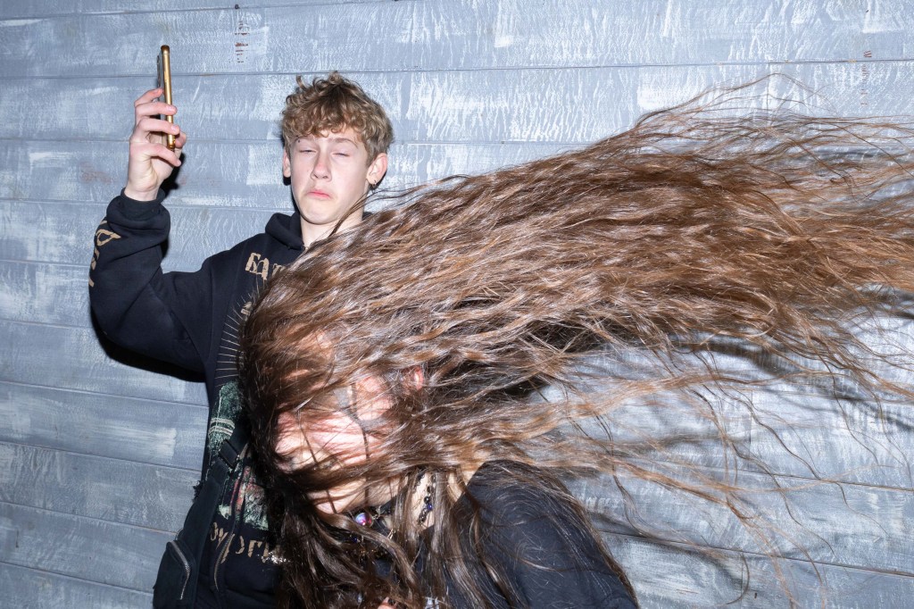One person headbangs while another holds their phone in the air